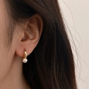 Élégantes boucles d'oreilles créoles dorées en U avec perle blanche sur mannequin