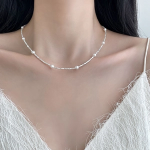 Close-up of minimalist white pearl and irregular silver bead necklace worn by a model