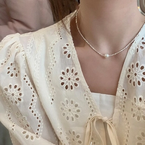Close-up of minimalist single white pearl necklace with crushed silver textured chain