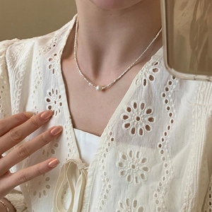 Detailed close-up of a white pearl necklace with silver beads on a model's neck