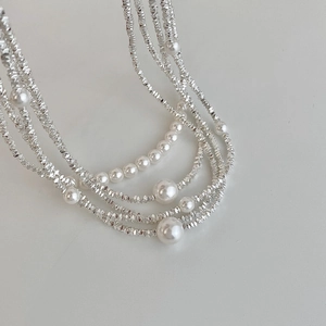 Detail of layered white pearl necklace with faceted silver metal beads in close-up view