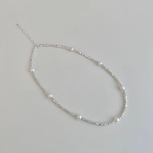 Macro shot of silver beaded necklace with seven round pearls and lobster clasp closure