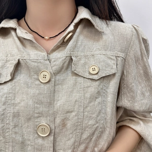 Detail of freshwater pearl on black crystal necklace paired with a linen shirt