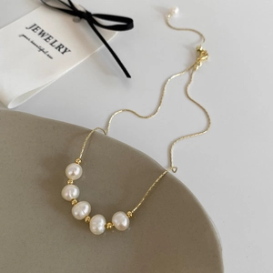 Close-up of five freshwater pearls and gold beads on a delicate snake chain necklace