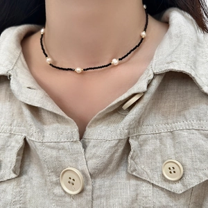 Close-up of black beaded choker necklace with freshwater pearls and gold plated accents