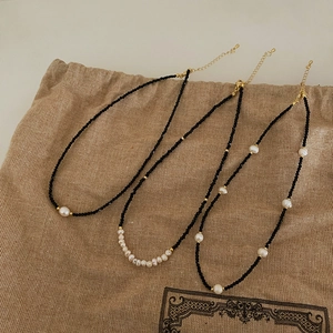 Detailed flat lay of three black crystal necklaces with freshwater pearls and gold beads
