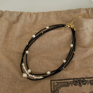 Detail of triple-layer black beaded necklace with freshwater pearls and gold-plated clasp