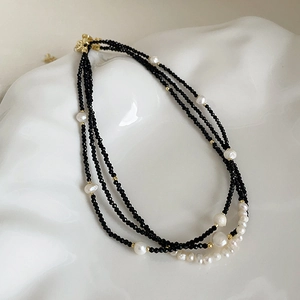 Detailed macro view of triple-layered black crystal and freshwater pearl necklace