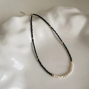 Minimalist black beaded necklace with baroque pearls and gold spacers on white ceramic