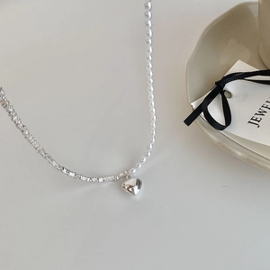Detail of silver heart pendant with pearl and textured silver beads necklace