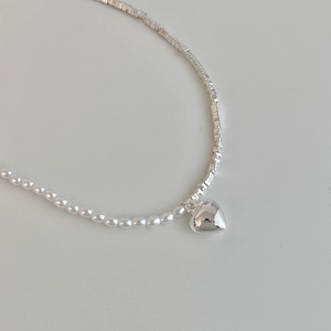 Detailed shot of a pearl and silver heart necklace with polished metallic finish