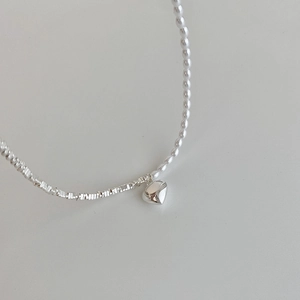 Minimalist pearl and silver heart necklace featuring asymmetrical beaded chain design