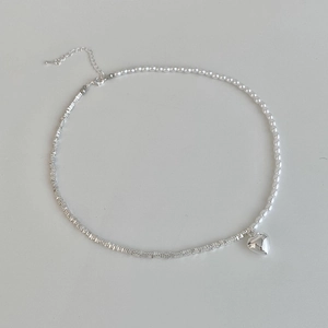 Detail of silver heart pendant with mixed pearl and metal square bead chain necklace