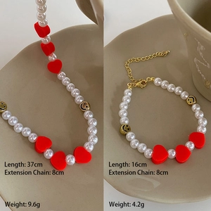 Détails du collier de perles et du bracelet avec cœurs rouges et perles de sourire dorées