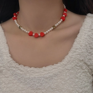 Gros plan d'un collier de perles avec cœurs rouges et smileys dorés sur un mannequin