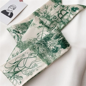 Détail de l'écharpe en soie étroite avec motif floral vert vintage et lettre B imprimée