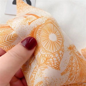 Gros plan détaillé de l'écharpe en soie sergé orange et blanc au motif H luxueux