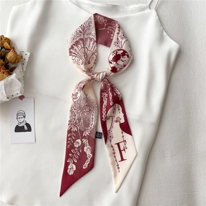 Détail d'un twilly en soie rouge et blanc avec des motifs floraux et la lettre F gravée