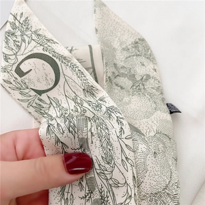 Gros plan d'un foulard en soie double face avec imprimés floraux et détail lettre G