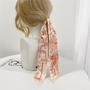 Détail d'un foulard étroit en satin crème avec motif d'art abstrait noué dans les cheveux