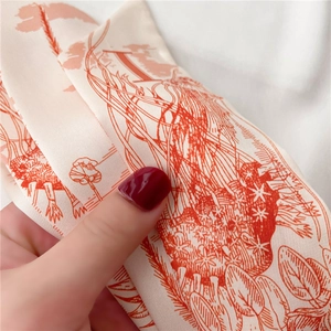 Détail d'un foulard en soie sergé avec illustrations florales orange sur fond crème