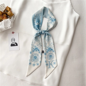Détail d'un foulard étroit en soie à motif floral et impression de la lettre K sur satin