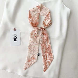 Détail d'une écharpe étroite en soie double face avec imprimé floral et lettre L