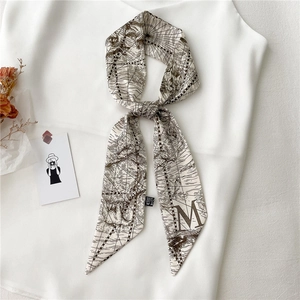 Détail d'un foulard étroit beige avec imprimé carte vintage et lettre M sur chemise