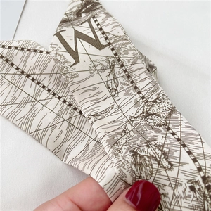 Détail macro d'un foulard en soie avec imprimé carte vintage et la lettre W gravée