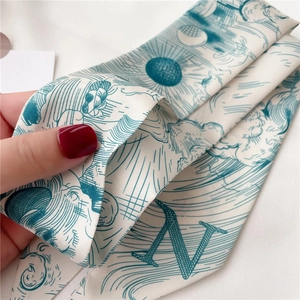 Gros plan d'un foulard étroit en soie avec motif lettre N bleu dessiné à la main