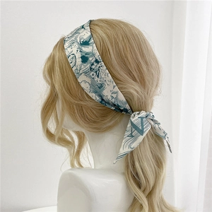 Détail d'un foulard en soie à vagues bleues avec la lettre N noué sur cheveux blonds