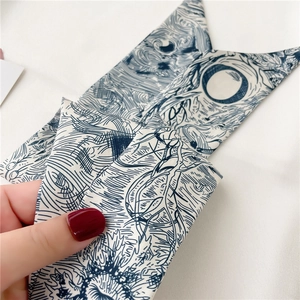 Détail d'un foulard étroit en sergé avec motifs bleus artistiques tenu par une main