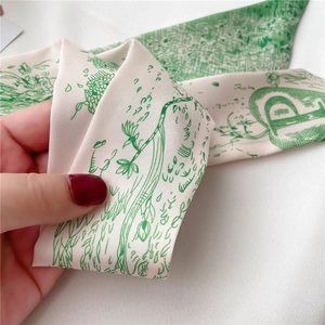 Détail d'un ruban en soie double face avec motifs floraux verts et lettres artistiques