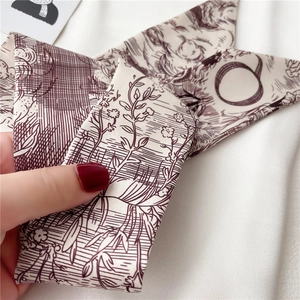 Gros plan d'un foulard étroit double face montrant la texture satinée et le motif vintage