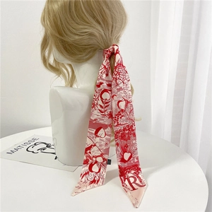 Détail d'un foulard en soie rouge et blanc noué sur une queue de cheval blonde