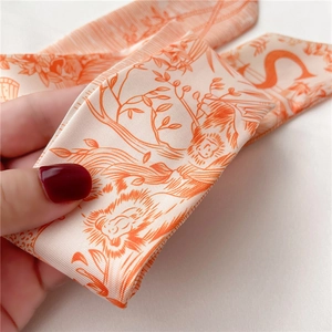 Gros plan détaillé d'un foulard en soie orange avec des motifs d'animaux et de fleurs