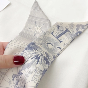 Détail de la lettre L sur un foulard en soie long avec motifs d'astrologie bleus