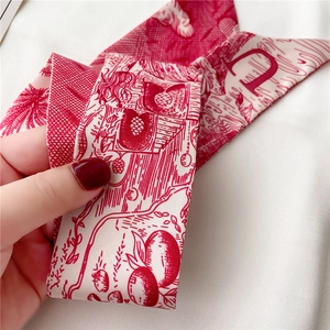 Détail d'un foulard en soie Toile de Jouy rouge et blanc avec palmiers et lettre D