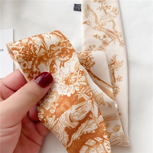 Gros plan d'un foulard twilly en soie avec motif oiseaux et fleurs et texture douce