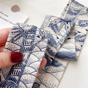 Gros plan du foulard twilly en polyester avec motifs de palmiers bleus et texture fine