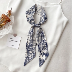 Mise à plat d'un foulard étroit en soie avec imprimé paysage bleu sur un caraco blanc