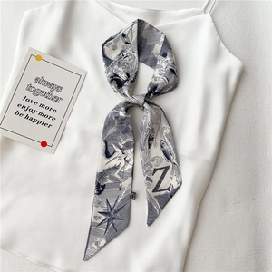Détail d'un foulard en soie étroit avec imprimé lettre Z attaché à un caraco blanc