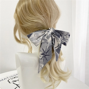 Détail d'un foulard en soie double face noué en ruban sur des cheveux blonds