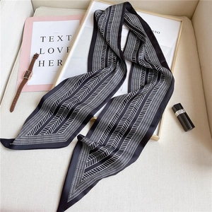 Detail of a black and white geometric narrow silk scarf with satin finish on elegant background