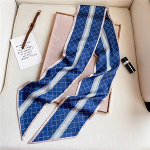 Detailed close-up of blue twilly silk scarf with yellow dots and striped grid patterns