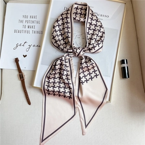 Detailed close-up of beige houndstooth skinny scarf with fine stitching and chic trim