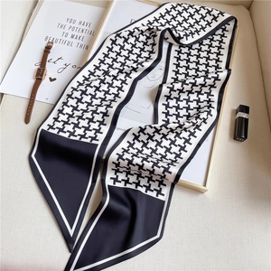 Close-up of elegant black and white houndstooth skinny silk scarf with classic border