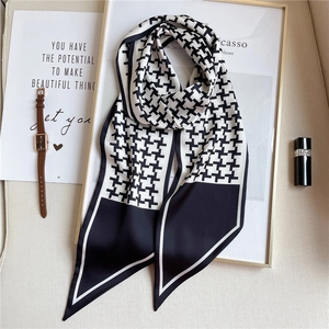 Macro shot of stylish houndstooth silk scarf with elegant watch and lipstick props