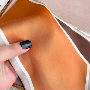 Detailed close-up showing soft silk texture and vibrant orange satin finish of the scarf
