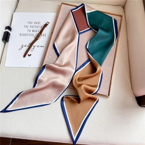 Detail of silk-like geometric scarf with pink and emerald colors on wooden tray